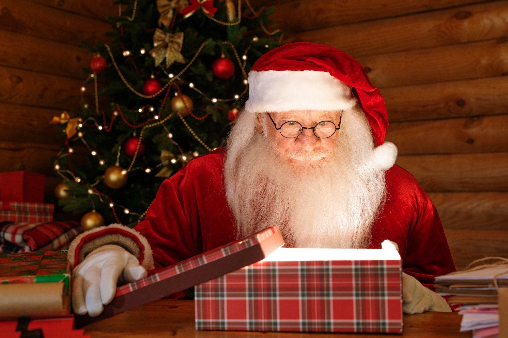 Santa Claus looking at light in open giftbox with amazement
