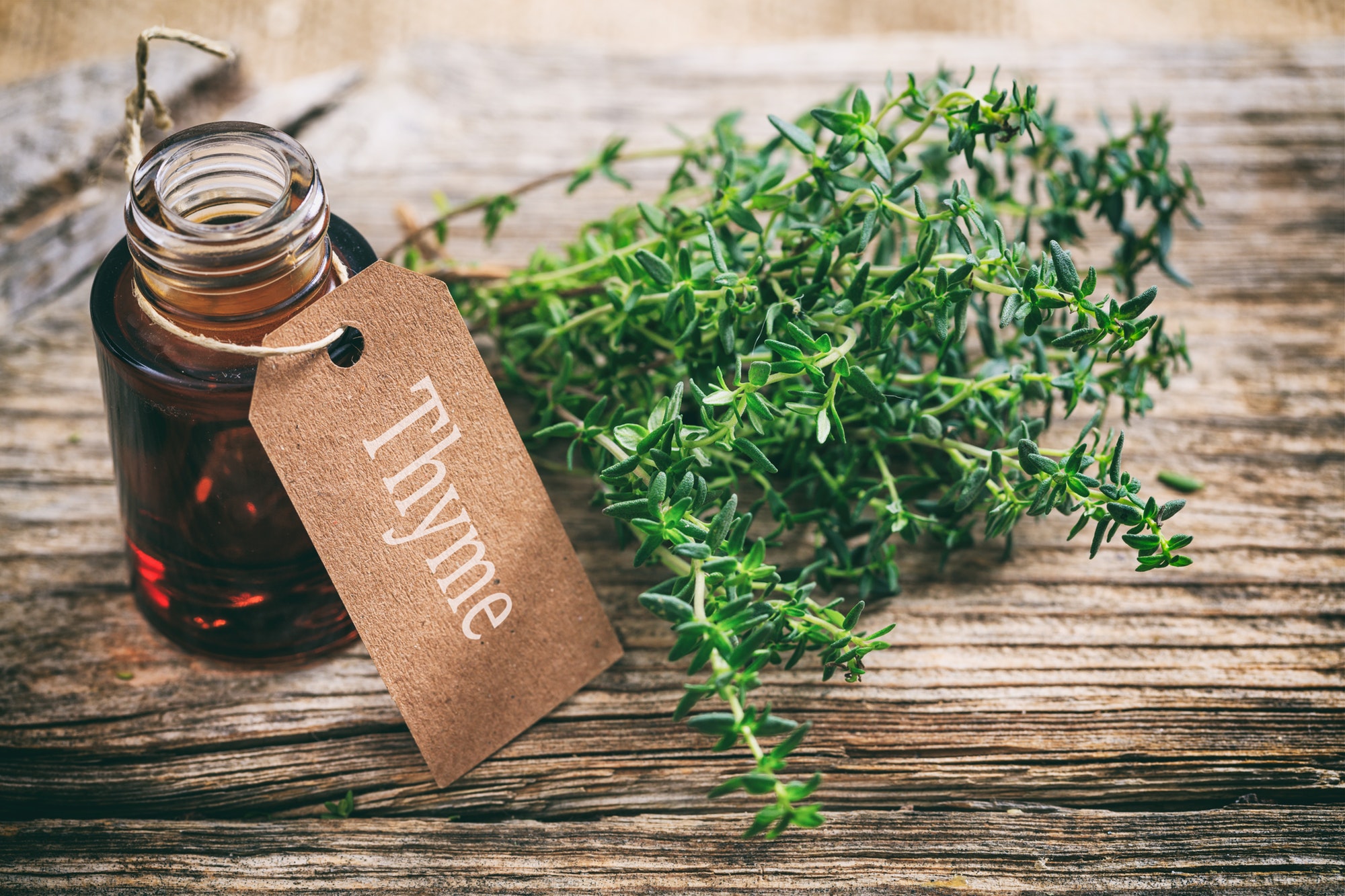 Thyme oil on wooden background