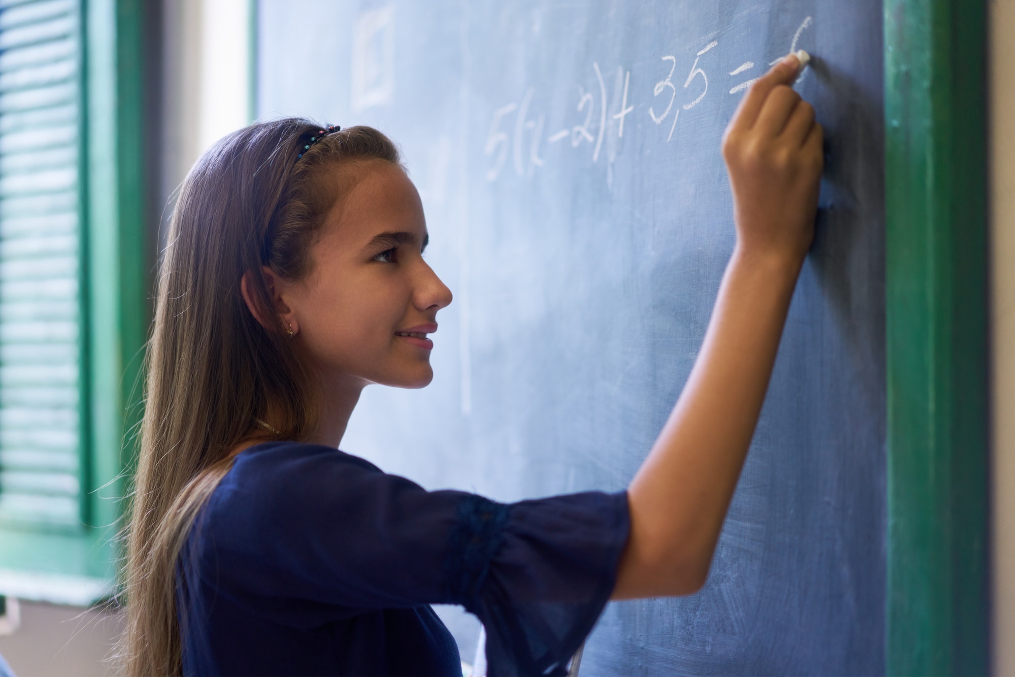 Girl Doing Math Exercise At Blackboard In High School Class